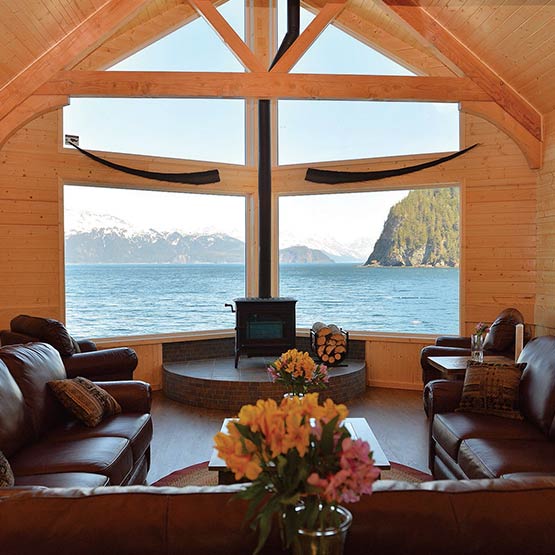 View through Kenai Fjords Wilderness Lodge's lounge, water is seen through the windows.